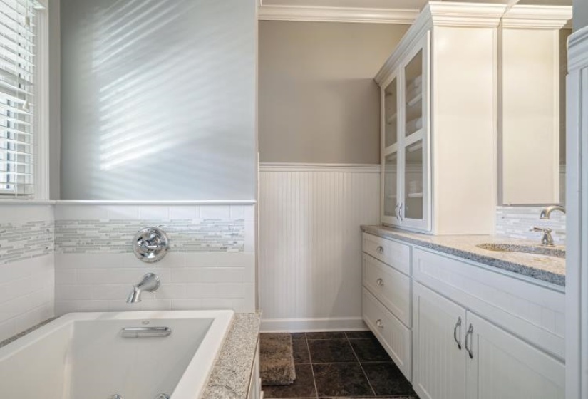 Full bath with a wainscoted wall, a tub with jets, ornamental molding, tile patterned floors, and vanity