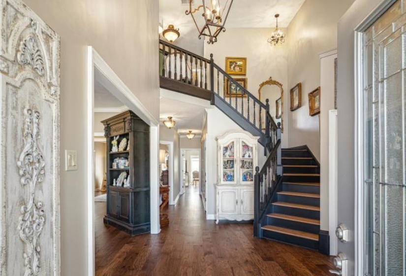 Foyer entrance featuring a notable chandelier, stairs, a high ceiling, and dark wood-type flooring