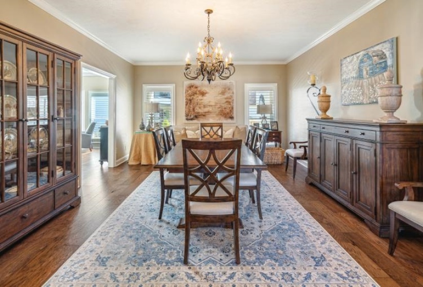 Dining room featuring ornamental molding, dark wood finished floors, a wealth of natural light, and a notable chandelier