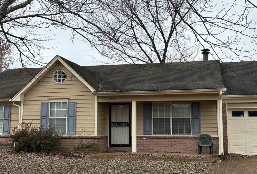 Ranch-style house featuring an attached garage, brick siding, a shingled roof, and a porch