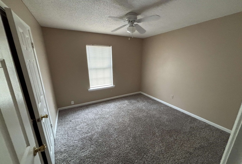 Carpeted spare room with a textured ceiling and a ceiling fan