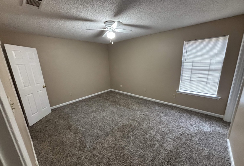Spare room with dark carpet, a textured ceiling, and a ceiling fan
