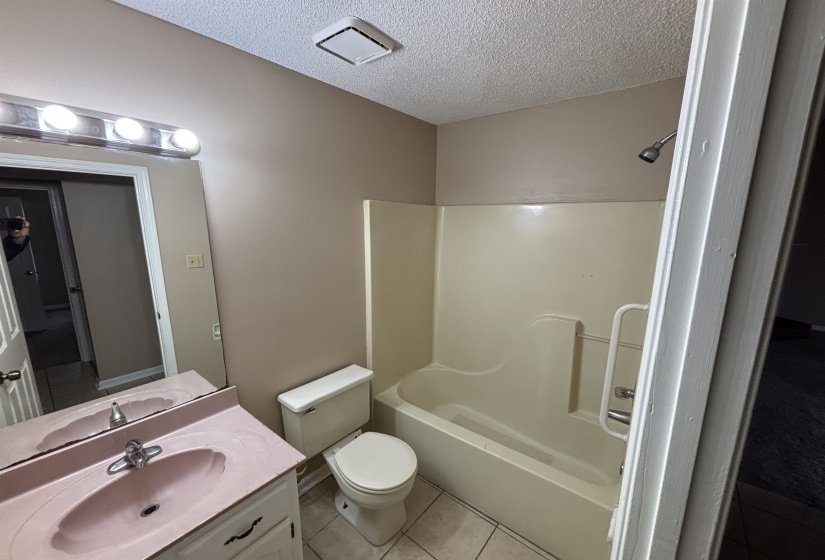 Bathroom with vanity, washtub / shower combination, a textured ceiling, and light tile patterned floors