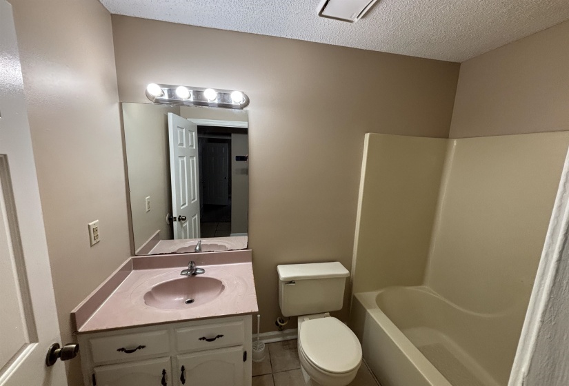 Bathroom with vanity, a textured ceiling, shower / tub combination, and tile patterned flooring