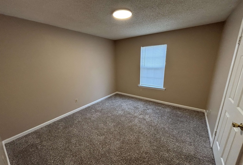 Carpeted empty room featuring baseboards and a textured ceiling