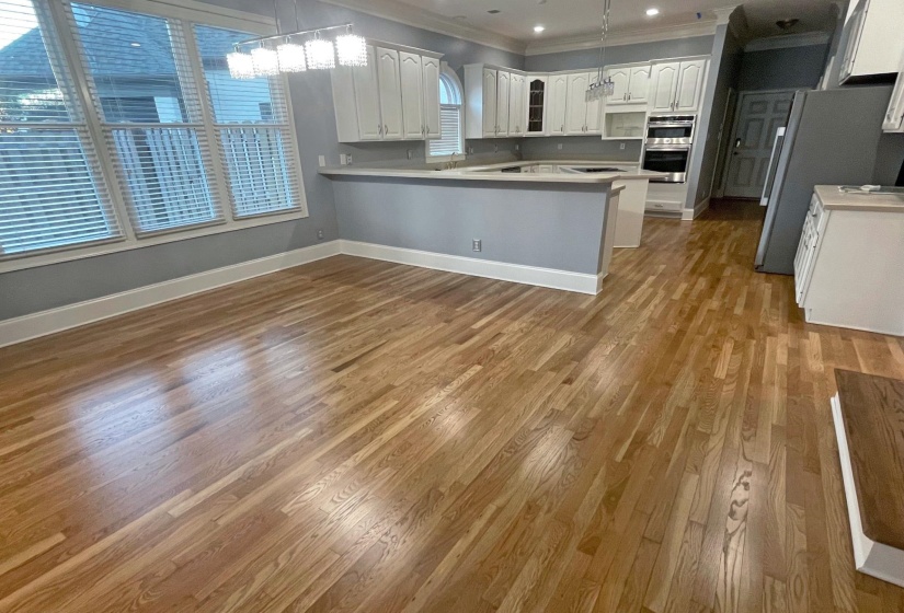Kitchen with glass insert cabinets, crown molding, white cabinets, a peninsula, and light wood finished floors