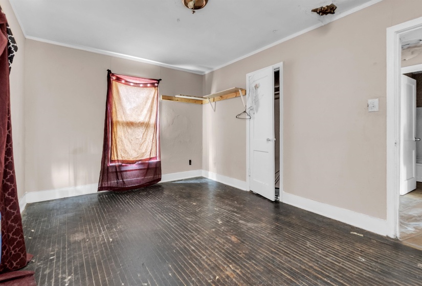 Unfurnished bedroom with crown molding and dark wood-style flooring