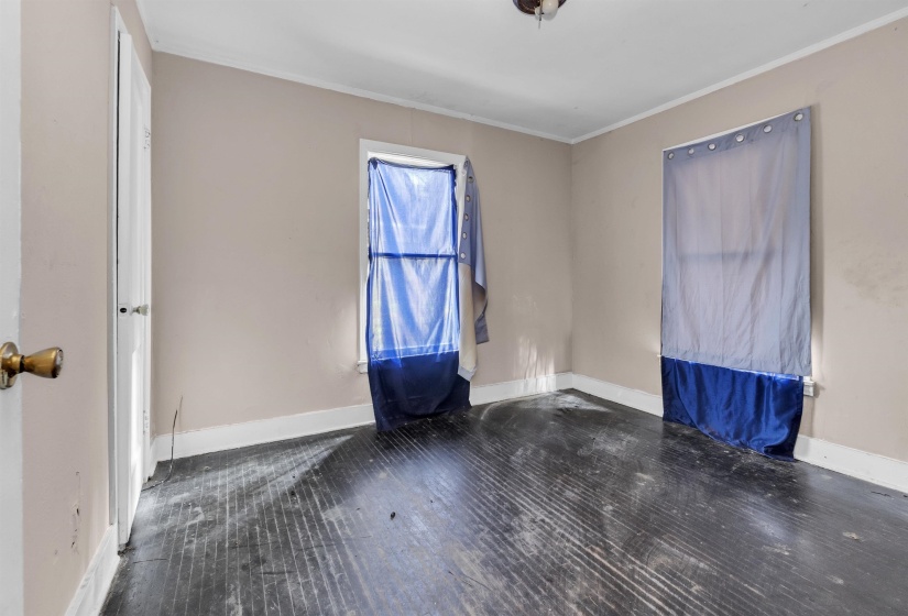 Spare room featuring crown molding and dark wood-style floors