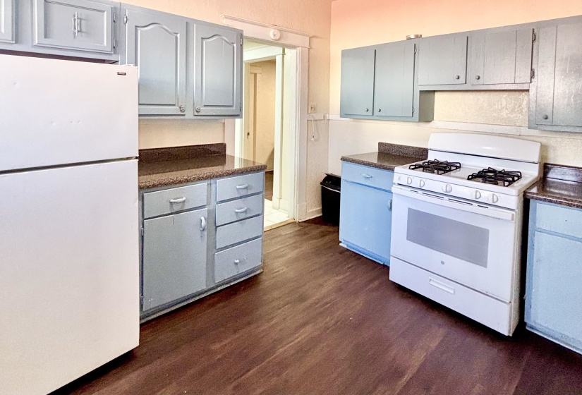 Kitchen featuring dark countertops, white appliances, dark wood-style floors, and gray cabinetry
