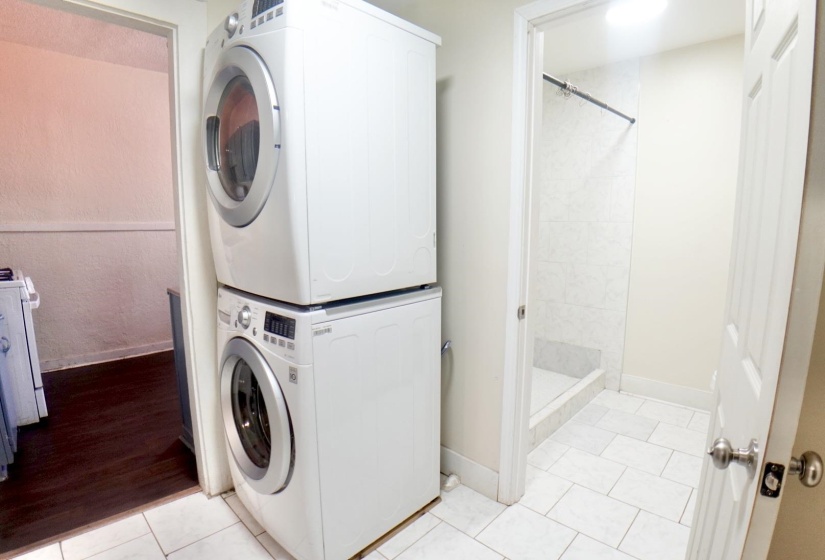 Laundry room with estacked washer and dryer and light tile patterned flooring