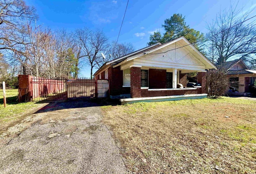 View of front of home featuring brick siding, a patio, and a gate