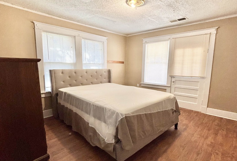 Bedroom featuring wood finished floors, ornamental molding, multiple windows, and a textured ceiling