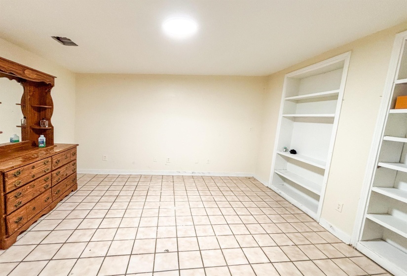 Unfurnished living room with built in shelves and light tile patterned floors