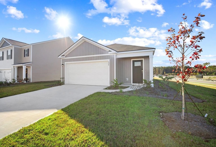 View of front of home with concrete driveway, a front yard, and an attached garage