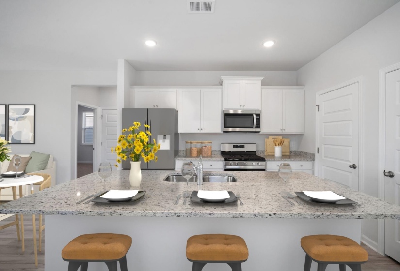 Kitchen with a kitchen breakfast bar, appliances with stainless steel finishes, light stone countertops, light wood finished floors, and white cabinets