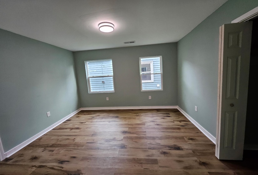 Empty room featuring dark wood-style flooring and baseboards