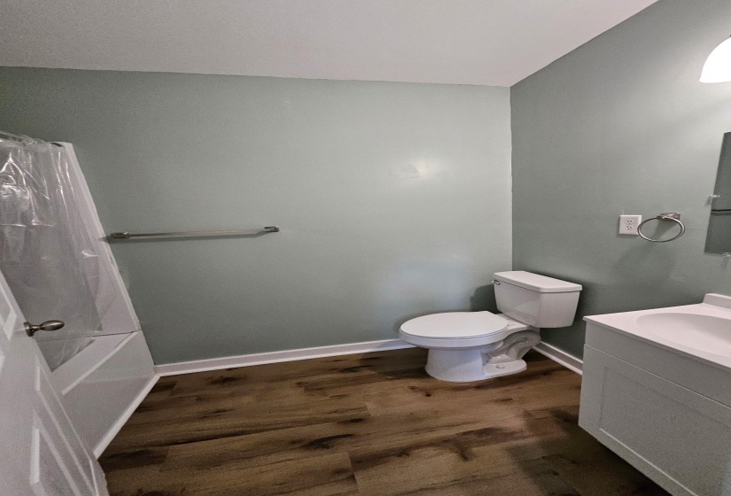 Bathroom with vanity, dark wood-style floors, and shower / bathtub combination with curtain