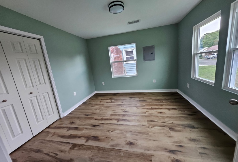 Unfurnished bedroom featuring wood finished floors, a closet, and electric panel