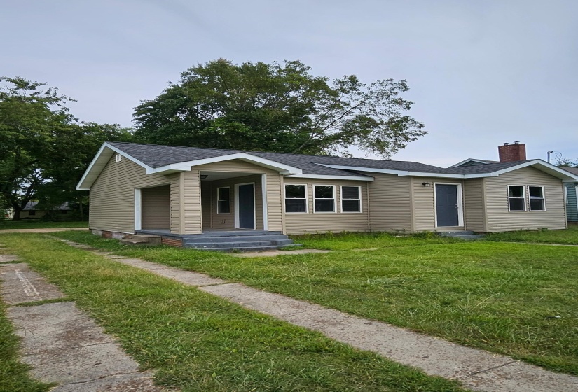 Ranch-style home featuring roof with shingles, a front yard, and a chimney