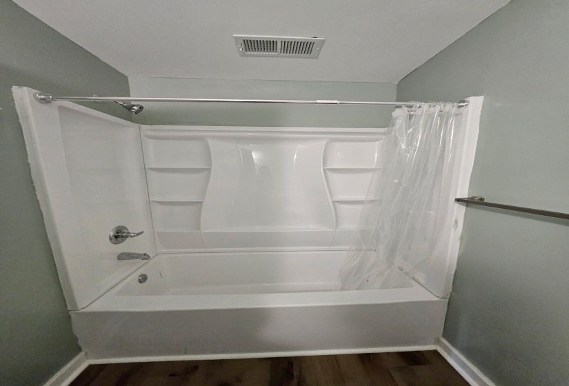 Full bath featuring shower / tub combo with curtain and dark wood-style flooring