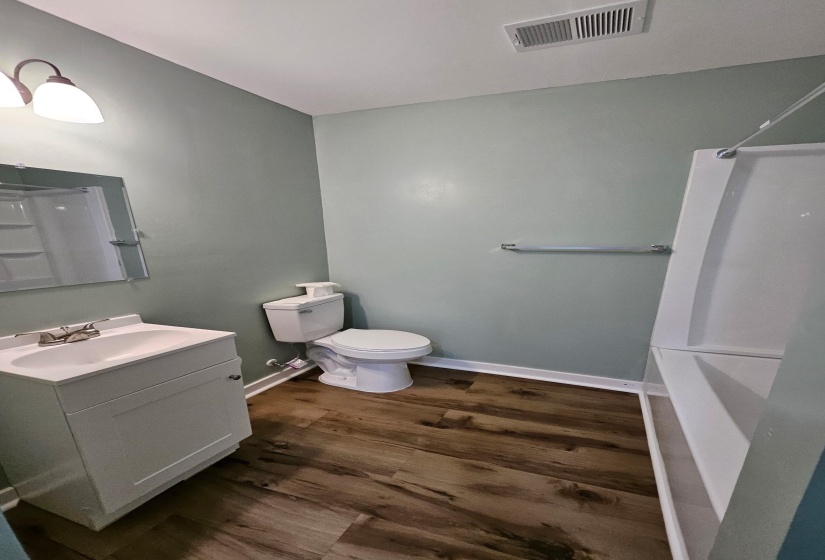 Bathroom featuring vanity, dark wood-style flooring, and shower / bathtub combination
