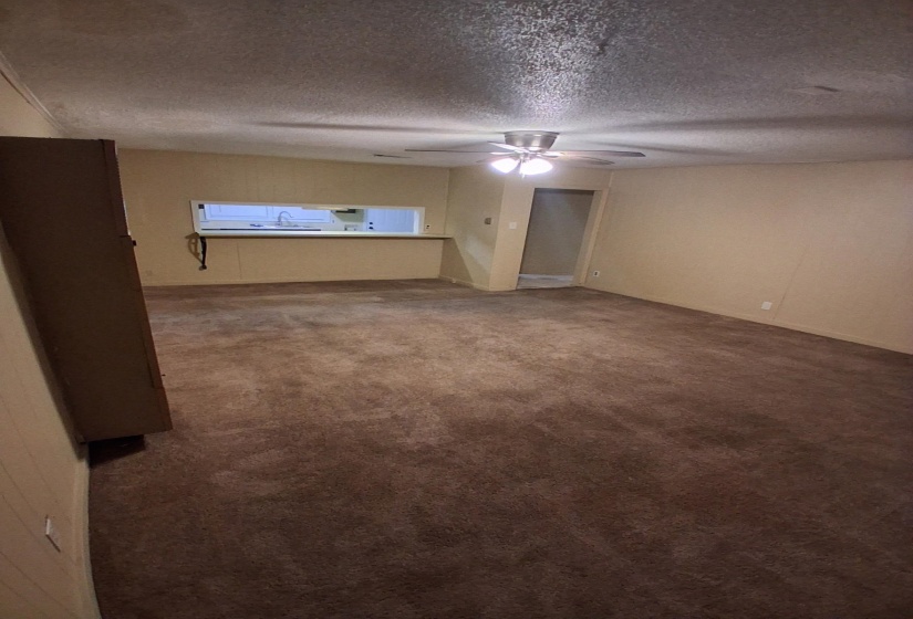 Empty room featuring dark carpet, a textured ceiling, and a ceiling fan