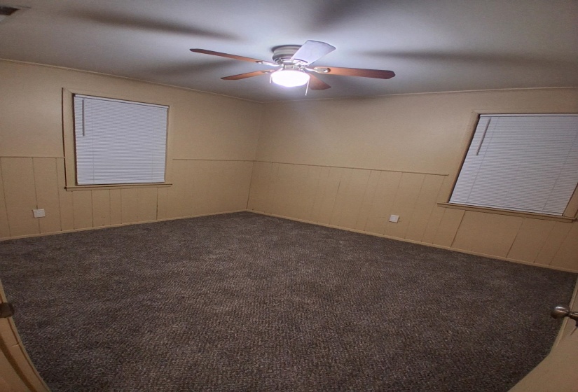 Spare room featuring carpet, wooden walls, and wainscoting