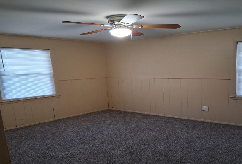 Unfurnished room featuring a wainscoted wall, ceiling fan, carpet flooring, and wood walls