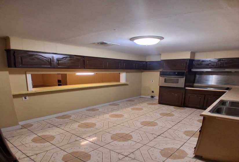 Kitchen featuring oven, dark brown cabinetry, light countertops, black electric stovetop, and under cabinet range hood