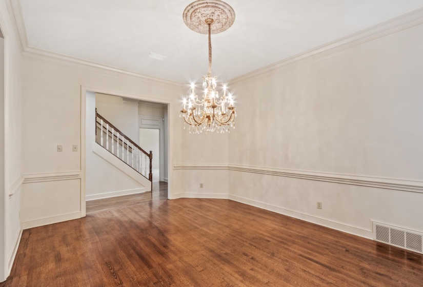 Formal room with hardwood flooring, a crystal chandelier, decorative ceiling medallion, extensive crown molding, and wainscoting
