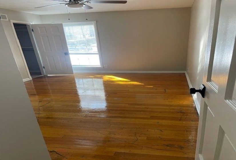 Empty room with hardwood / wood-style floors and a ceiling fan