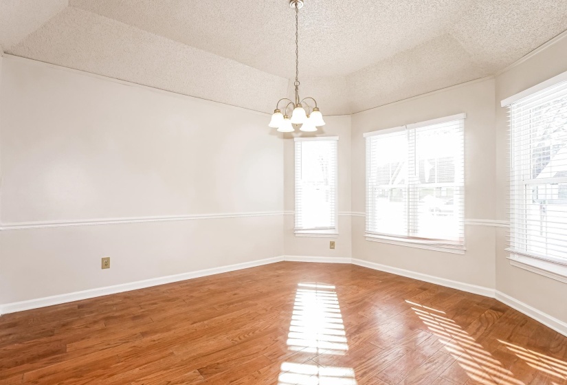 Unfurnished room with plenty of natural light, wood finished floors, and a chandelier