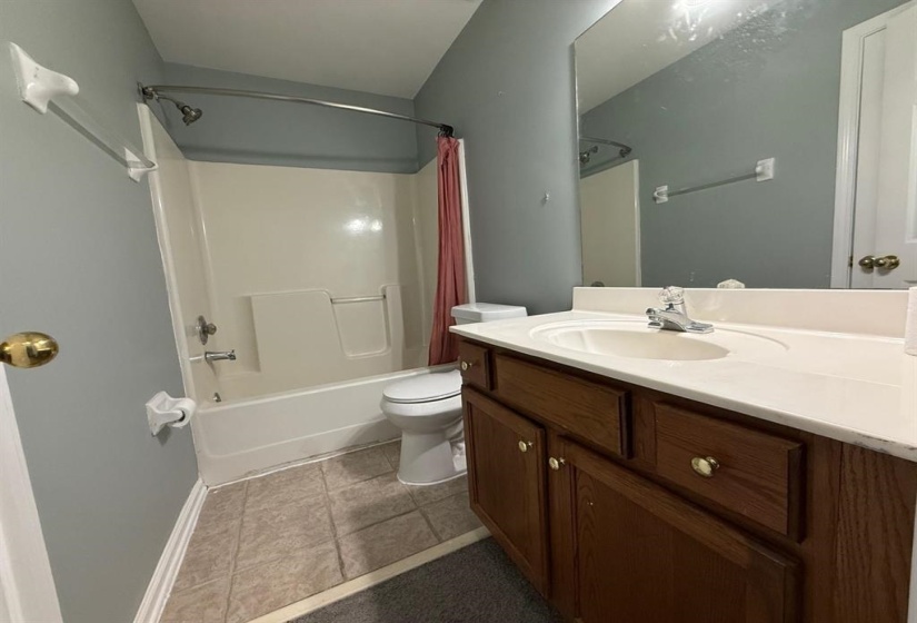 Bathroom featuring vanity, shower / tub combo, and dark tile patterned floors