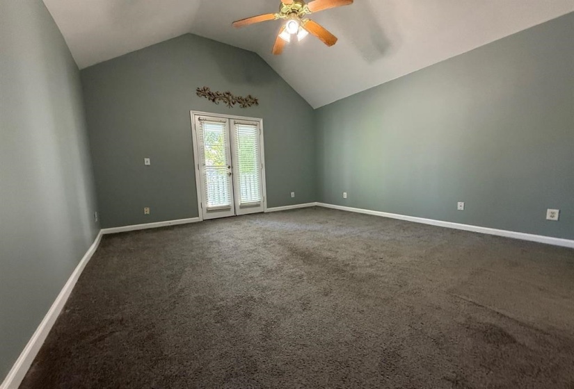 Unfurnished room featuring ceiling fan, dark carpet, and a high ceiling