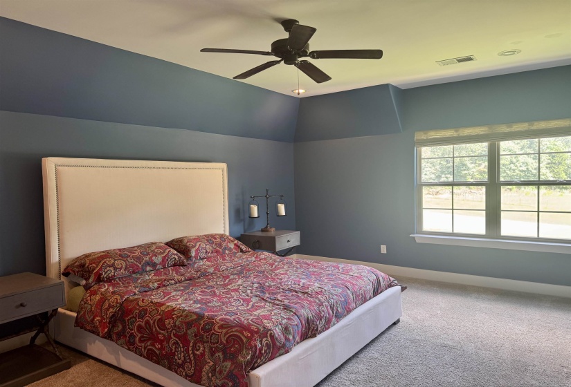 Carpeted bedroom featuring ceiling fan and vaulted ceiling