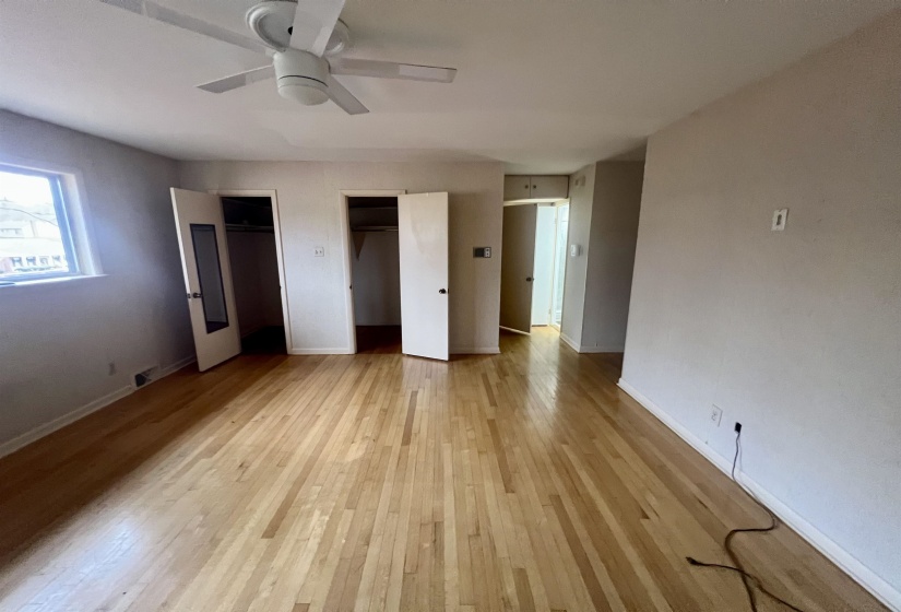 Unfurnished bedroom with two closets, light wood-style floors, and a ceiling fan