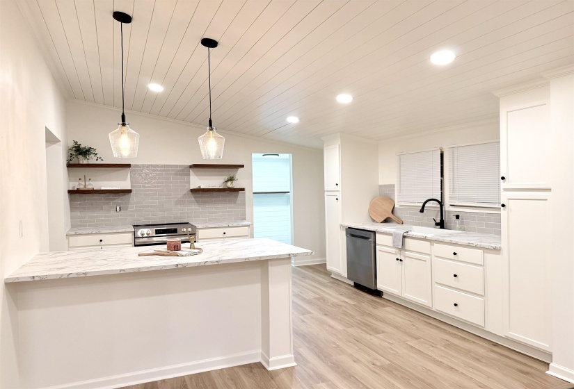 Kitchen with backsplash, a peninsula, light stone counters, wood ceiling, and stainless steel appliances