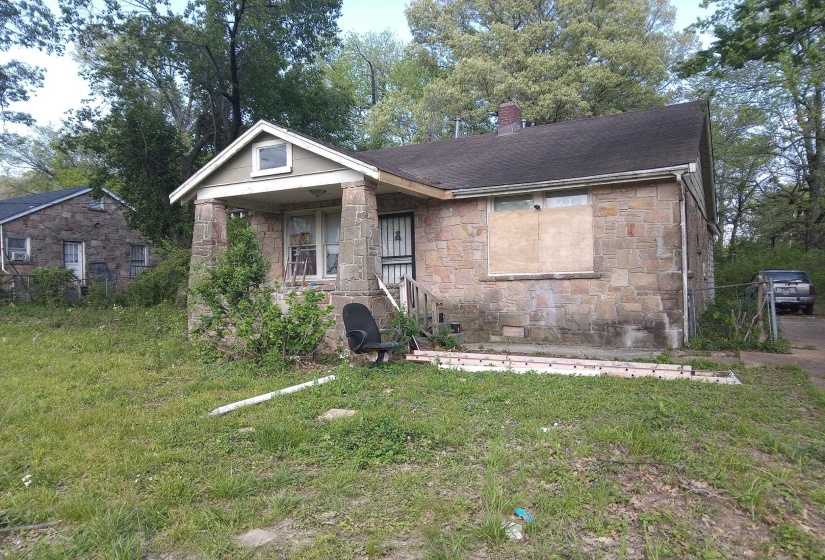 View of front of home featuring roof with shingles, a front lawn, stone siding, and a chimney