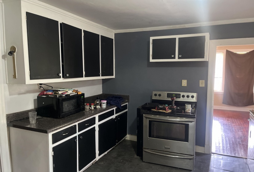 Kitchen featuring ornamental molding, dark stone countertops, black microwave, stainless steel range with electric stovetop, and dark cabinetry