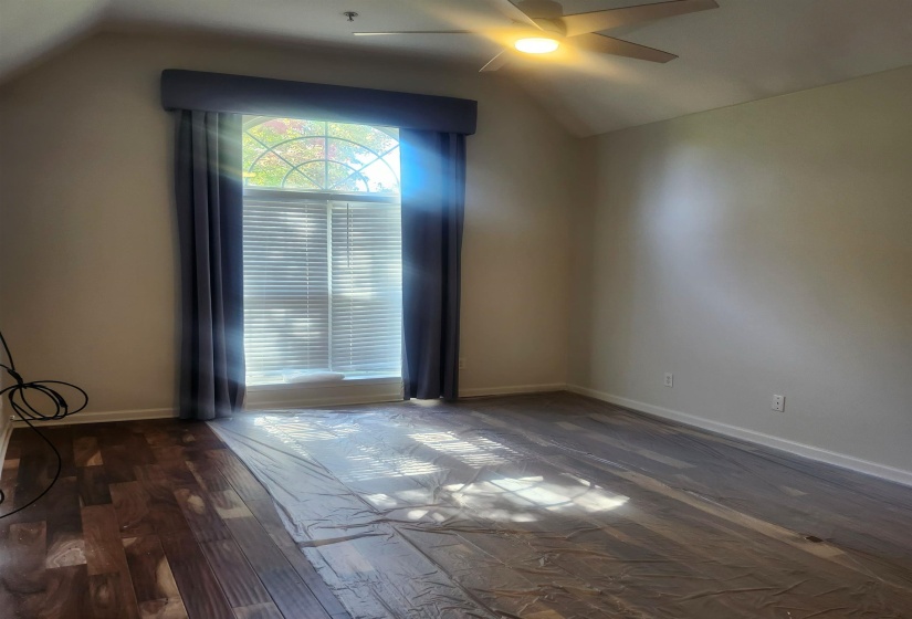 Unfurnished room featuring a ceiling fan, lofted ceiling, and dark wood finished floors
