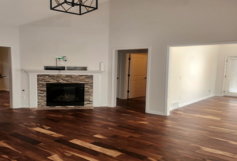 Unfurnished living room with a tiled fireplace, dark wood finished floors, and a high ceiling