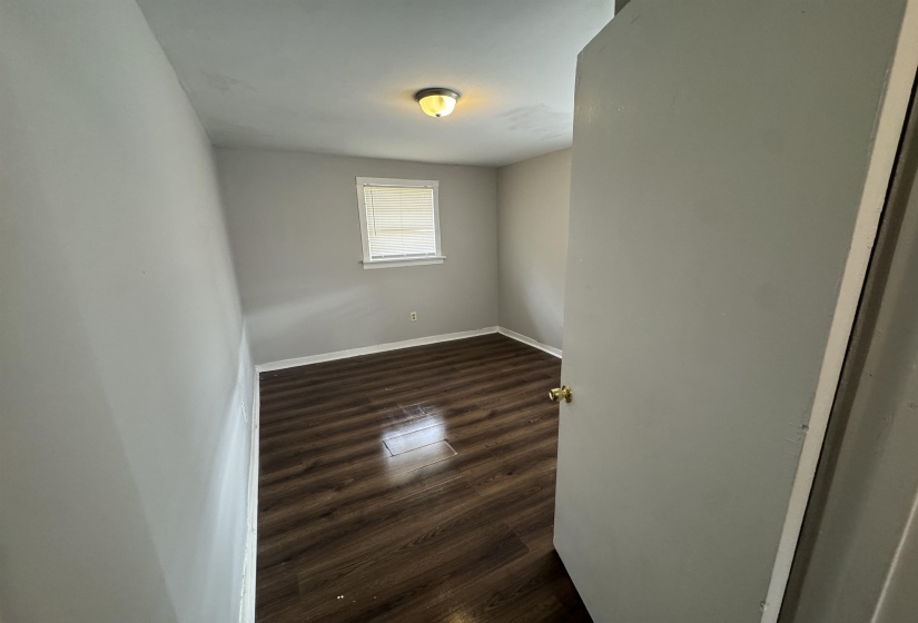 Spare room featuring dark wood-style flooring and baseboards