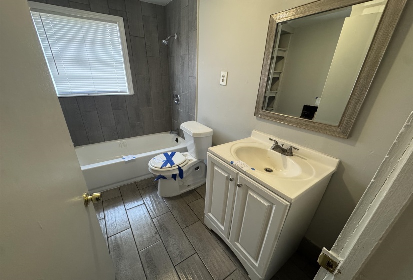 Bathroom featuring vanity, tub / shower combination, and wood tiled floors