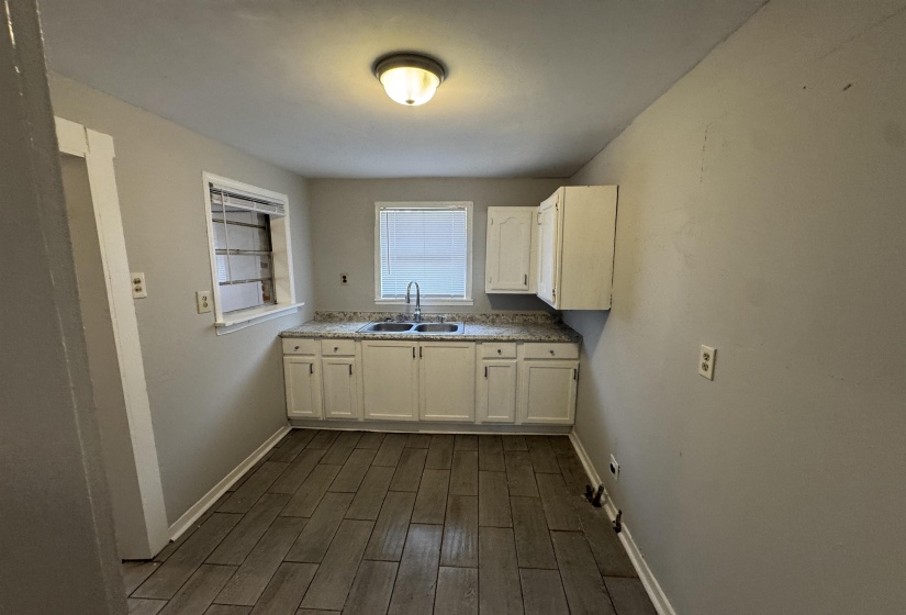 Kitchen featuring wood tiled floors, white cabinets, and light countertops