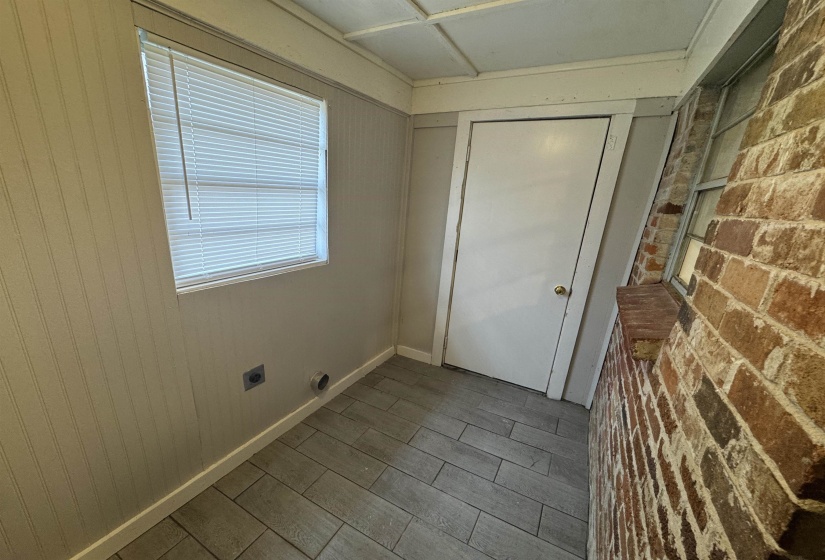 Laundry area with brick wall, wood tiled floors, and hookup for an electric dryer