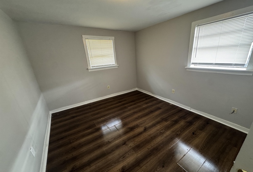 Spare room featuring dark wood-style flooring and baseboards