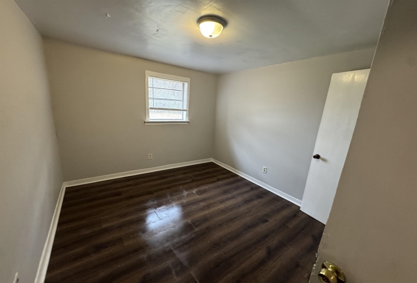 Spare room featuring dark wood-type flooring and baseboards
