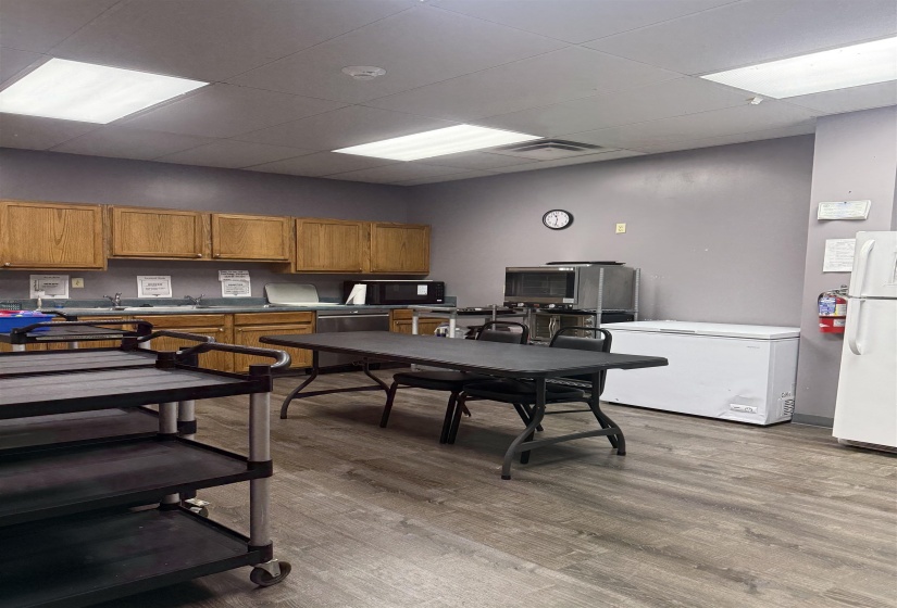 Kitchen featuring wood finish cabinets, a paneled ceiling, freestanding refrigerator, dishwasher, and black microwave