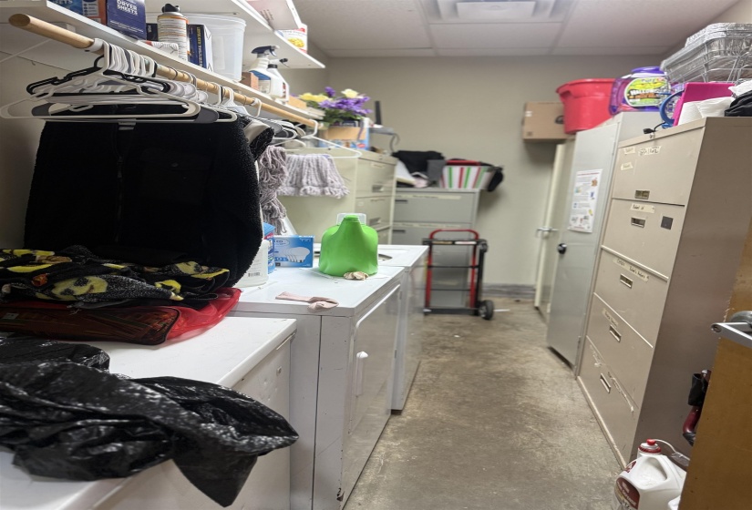 Laundry area featuring concrete floors, washing machine and clothes dryer, and a paneled ceiling
