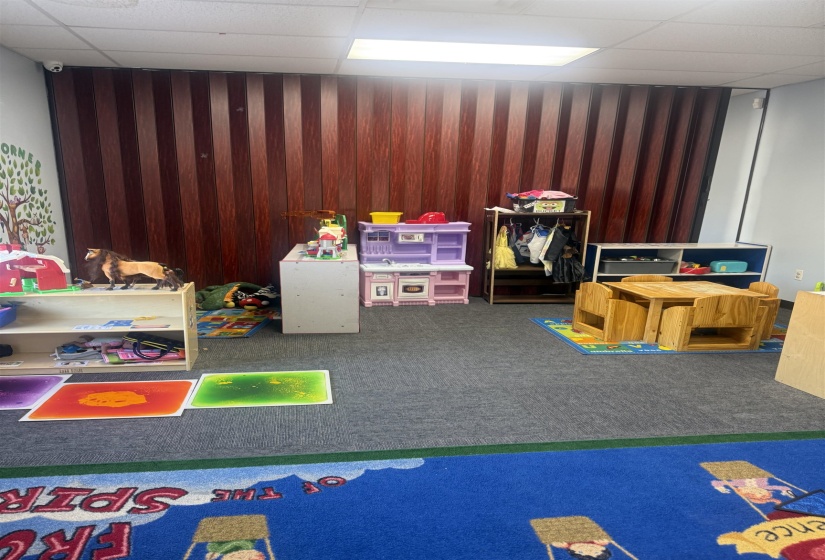 Playroom featuring a drop ceiling, carpet flooring, and wooden walls